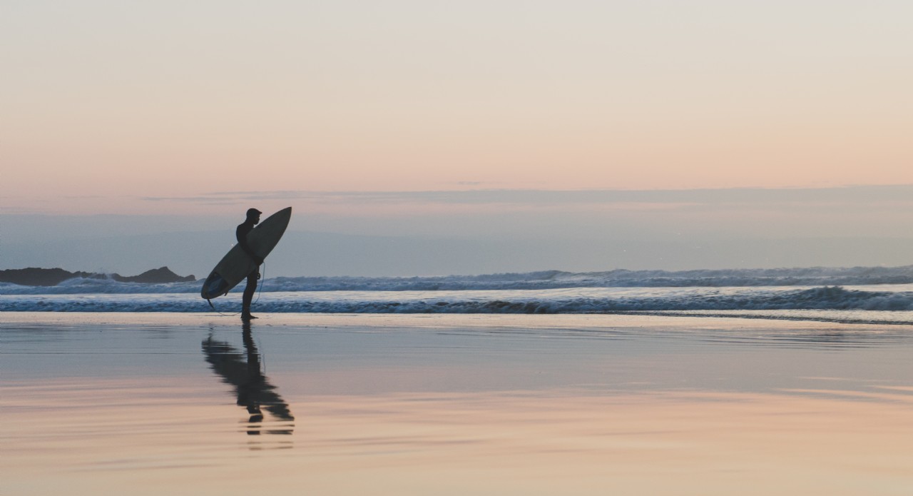 Solitary Surfer on a Calm Beach | Coastal Retreats